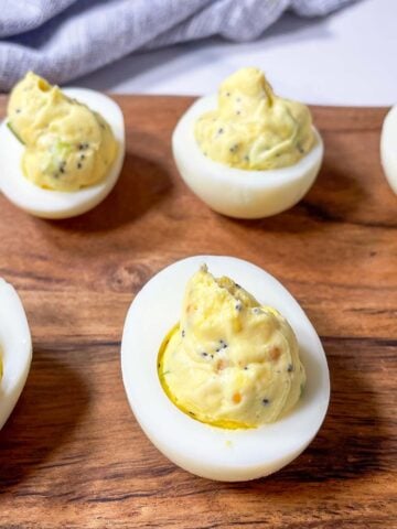 everything bagel deviled eggs with cream cheese on a wooden board.