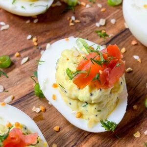 everything bagel deviled eggs with cream cheese and smoked salmon on a wooden board.