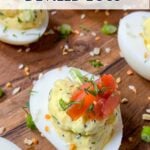 everything bagel deviled eggs with cream cheese and smoked salmon on a wooden board.