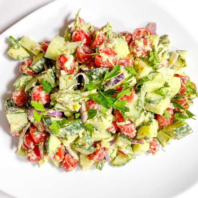 creamy cucumber tomato salad in a white salad bowl.