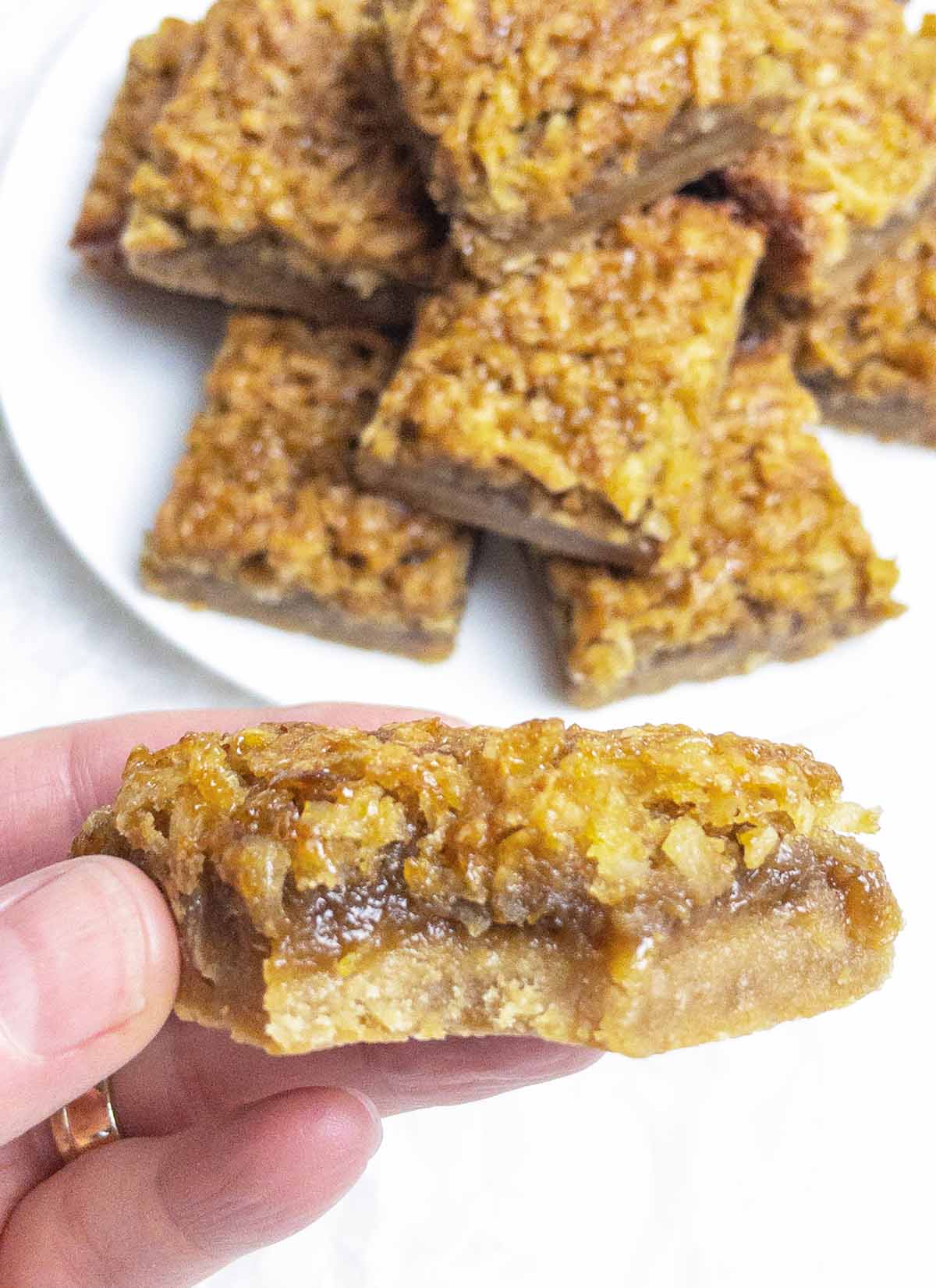 hand holding a coconut dream bar with a bite taken out.