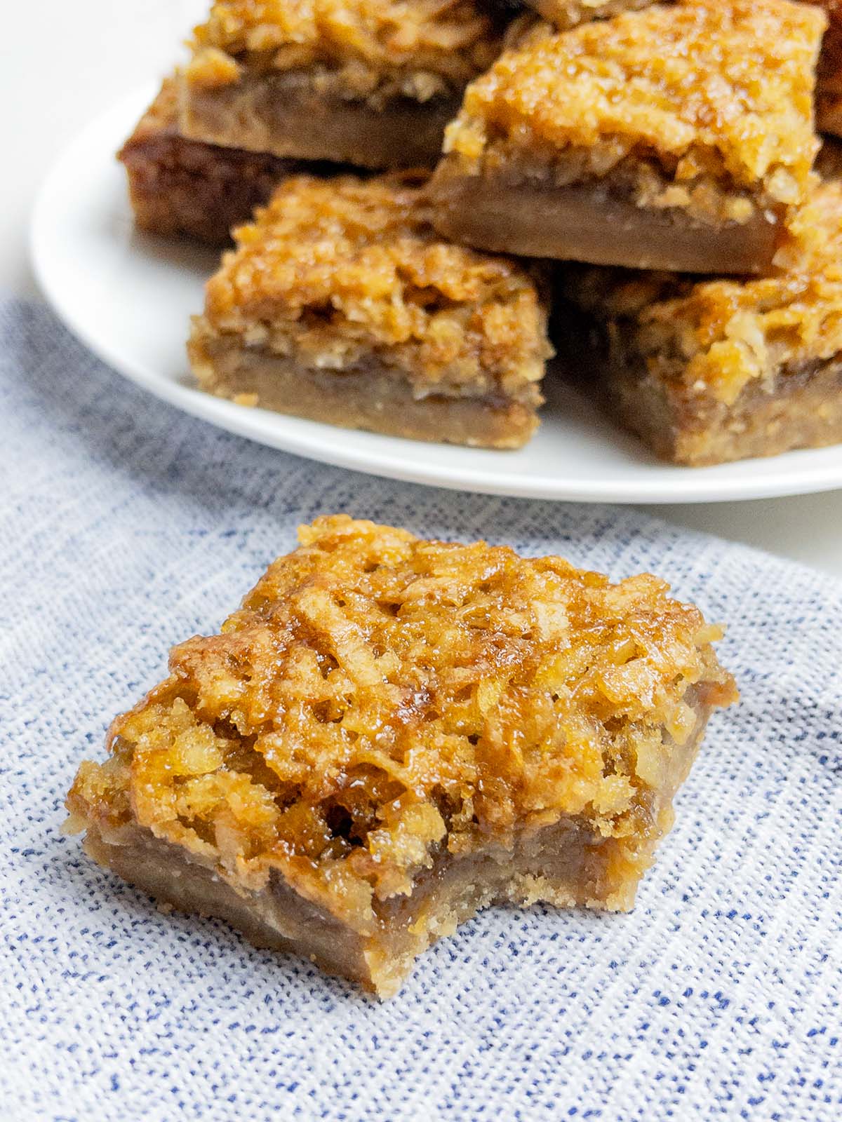 coconut dream bar with a bite taken out on a blue napkin.