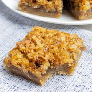 coconut dream bar with a bite taken out on a blue napkin.
