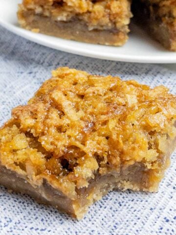 coconut dream bar with a bite taken out on a blue napkin.