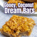 coconut dream bar with a bite taken out on a blue napkin.