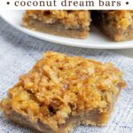 coconut dream bar with a bite taken out on a blue napkin.