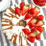 strawberry angel food cake topped with cream cheese glaze and fresh strawberries.