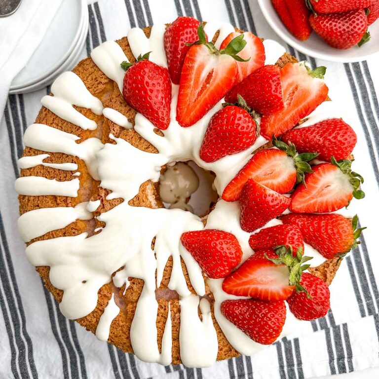 strawberry angel food cake topped with cream cheese glaze and fresh strawberries.