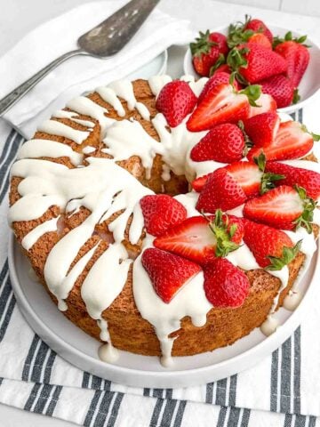 strawberry angel food cake topped with cream cheese glaze and fresh strawberries.