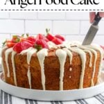 hand holding a knife cutting into strawberry angel food cake.