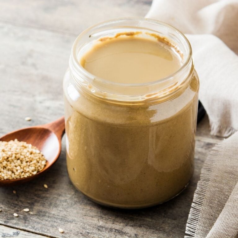 jar of tahini and a wooden spoon with sesame seeds