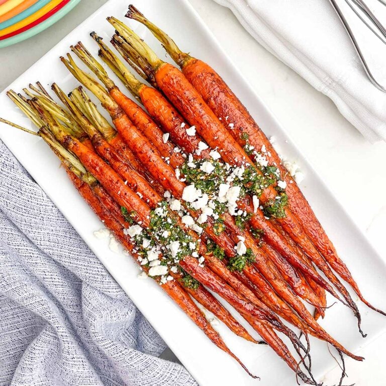 maple balsamic glazed carrots topped with feta and chimichurri on a white platter