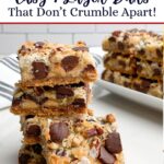 hello dolly bars cut into squares stacked on a white countertop.