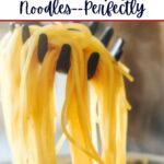 a pasta fork holding up a serving of cooked spaghetti.