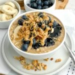 white bowl of powdered peanut butter overnight oats topped with blueberries and peanut butter.