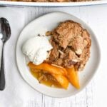 white plate with peach cobbler and ice cream
