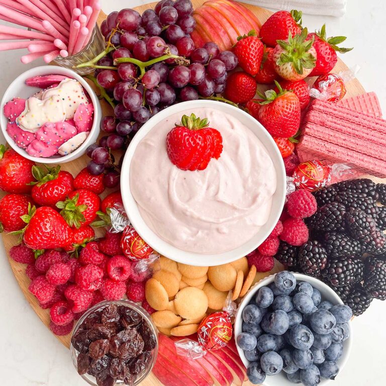 strawberry marshmallow fluff in a white bowl on a fruit board