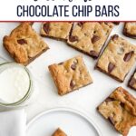 toll house cookie bars on a white countertop next to a glass of milk.