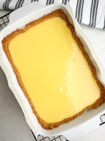baked lemon bars with graham cracker crust in white baking pan on wire rack
