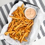 cooked frozen seasoned fries in pan with parchment paper and dipping sauce