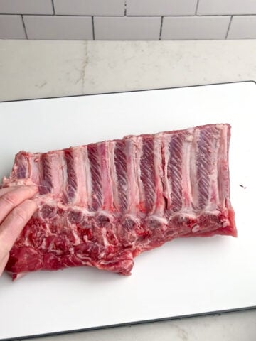 ribs with silverskin removed on a white cutting board.