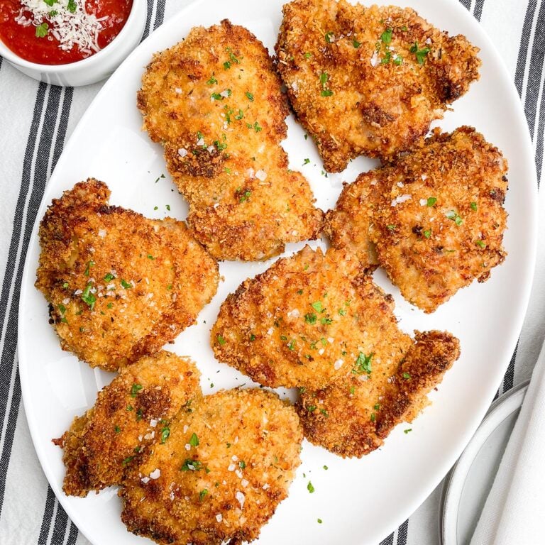 air fryer panko chicken thighs on a white platter next to a bowl of marinara