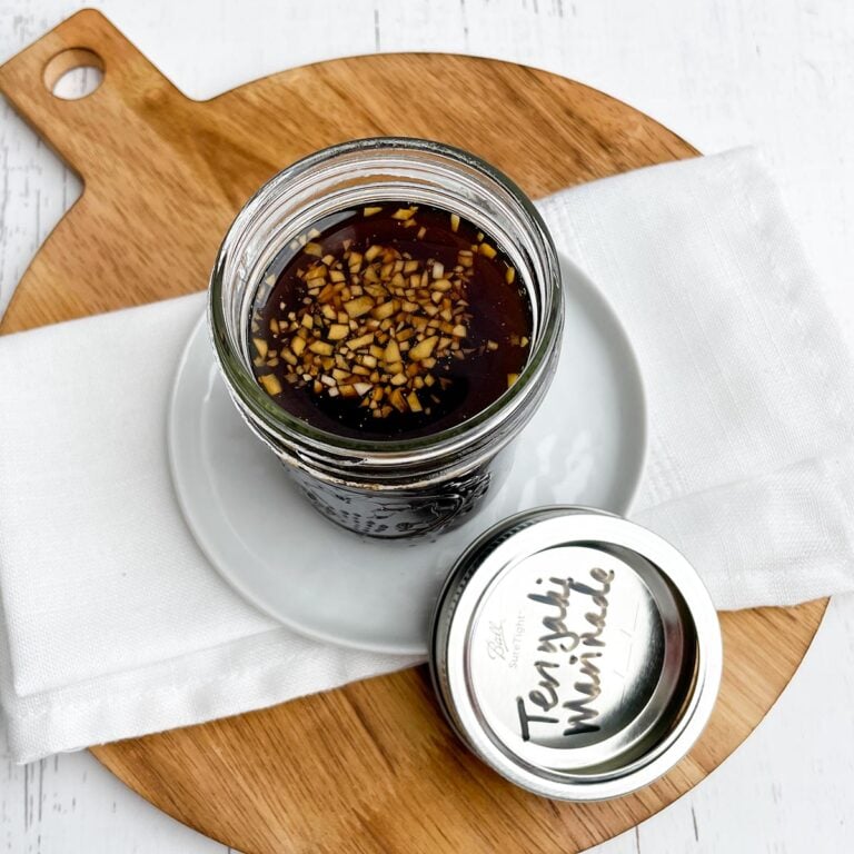 teriyaki marinade in a mason jar on a white plate and white napkin on a wooden cutting board