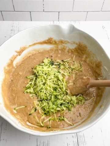 shredded zucchini in banana zucchini bread batter in white mixing bowl