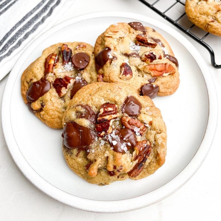 Three chocolate chip pecan cookies on a white plate