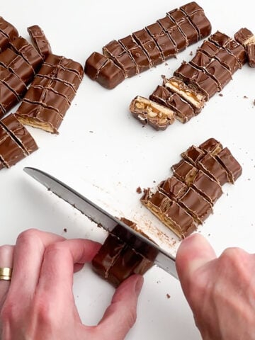 hands holding a knife and chopping Snickers bars