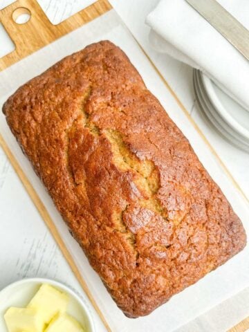 loaf of pancake mix banana bread on white parchment on a wooden cutting board