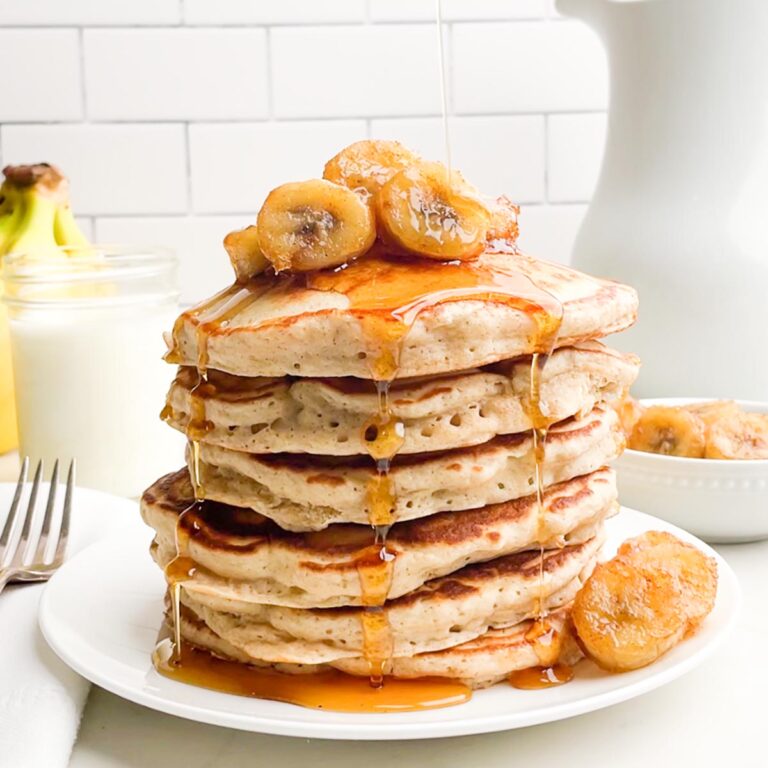 stack of banana pancakes from pancake mix topped with bananas and maple syrup