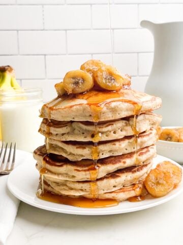 stack of banana pancakes from pancake mix topped with bananas and maple syrup