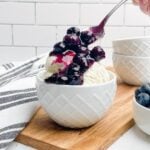 spoon dropping blueberry compote onto a bowl of vanilla ice cream