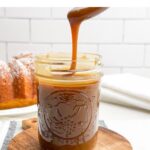spoon drizzling caramel sauce without cream into a mason jar.