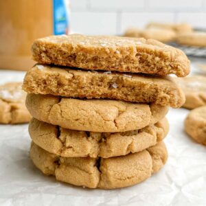 a stack of brown butter peanut butter cookies on parchment paper.