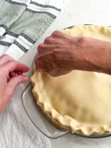 using hands to crimp pie dough together.