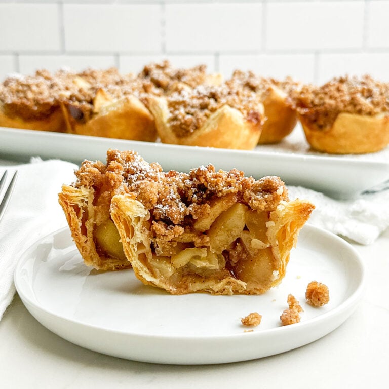 mini puff pastry apple pie cut in half on a white plate