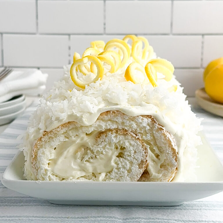 lemon cake roll with coconut on a white platter.