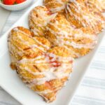baked and glazed mini strawberry pies on a white platter.