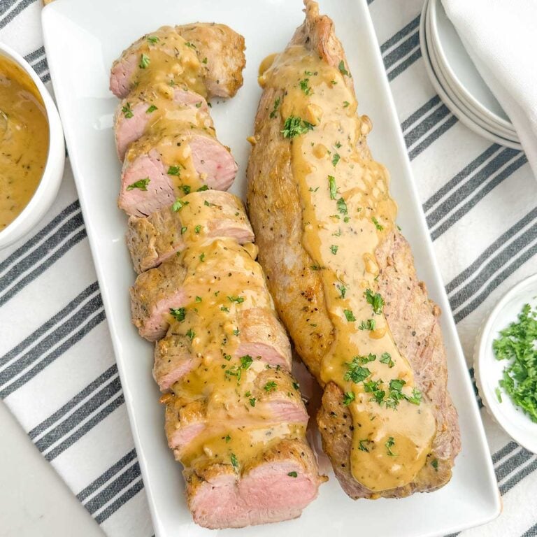 pork tenderloins with mustard sauce on white platter.