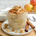side view of applesauce overnight oats in a mason jar topped with chopped apples and granola.