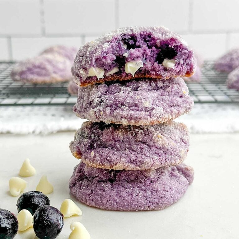 stack of lemon blueberry cookies with a half cookie on top.
