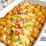 Big Mac tater tot casserole topped with lettuce, pickles. onions, tomatoes, sauce, and sesame seeds.