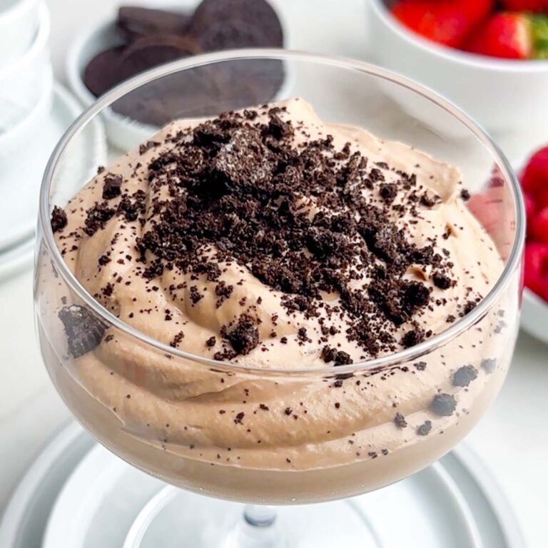 milk chocolate mousse in a clear stemmed glass topped with crushed Oreos.
