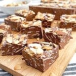 squares of chocolate almond nougat on a wooden cutting board.