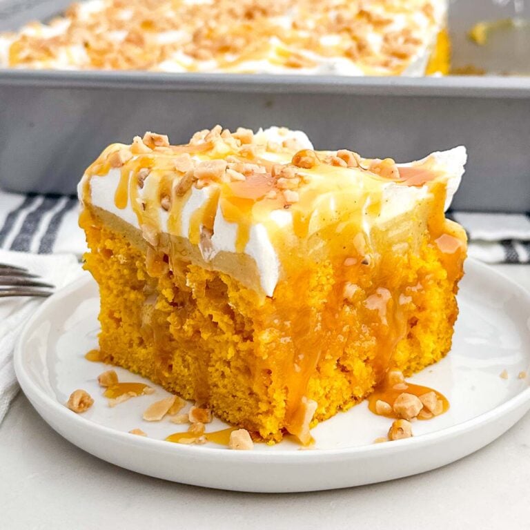 piece of pumpkin poke cake on a white plate.