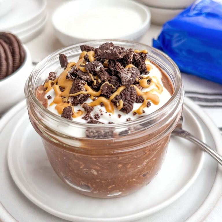 cookies and cream overnight oats topped with yogurt, Oreos, and peanut butter in a mason jar.