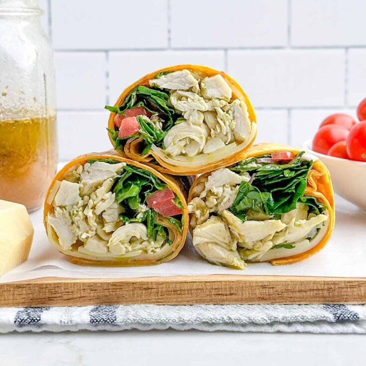 three halves of an italian wrap stacked on a white plate.