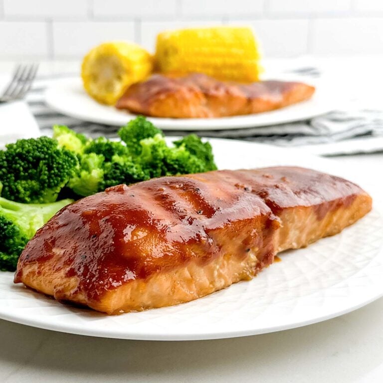 baked bbq salmon on a white plate with broccoli.